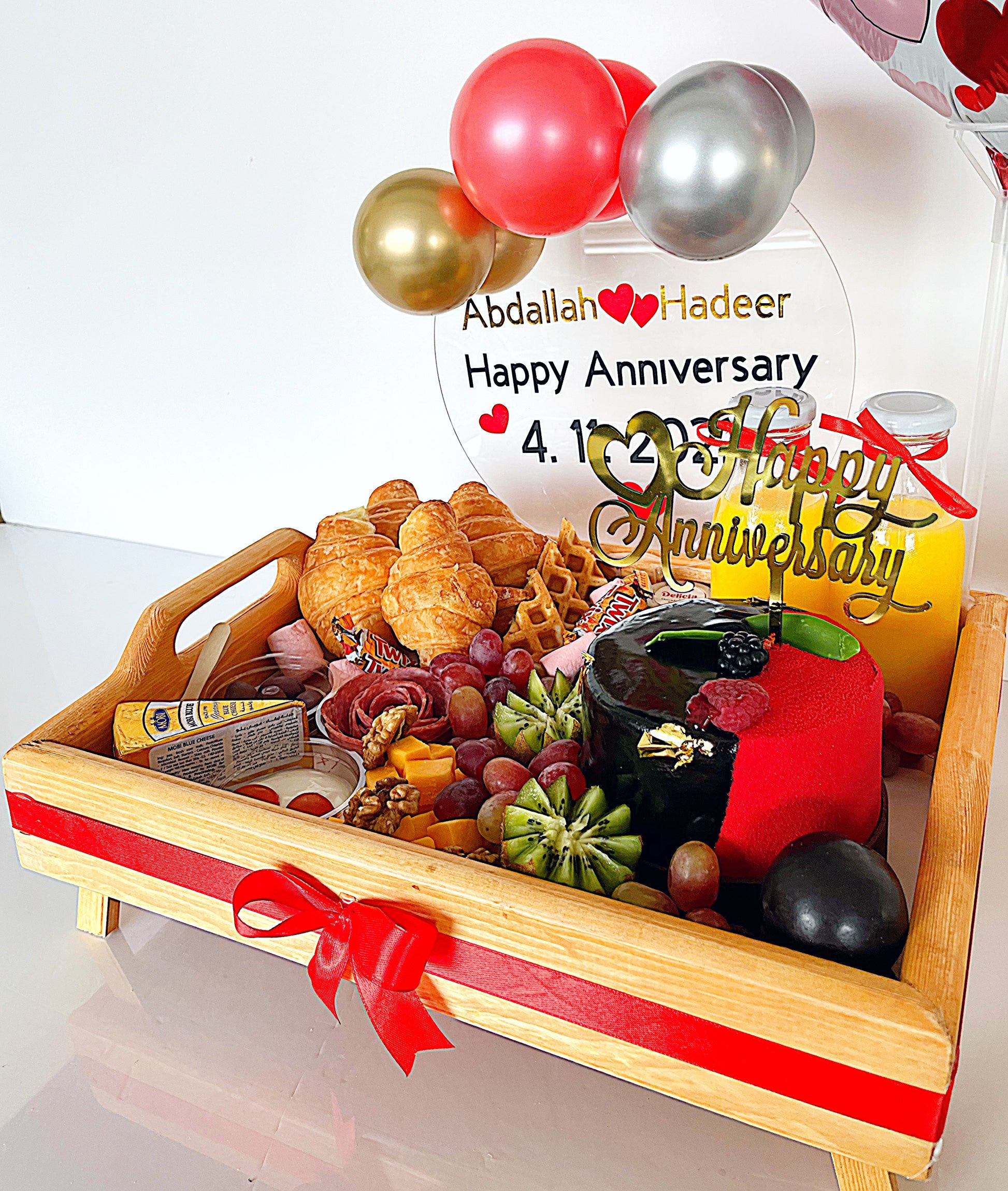 Decorative tray with food items and balloons, featuring a personalized 'Happy Anniversary' message.