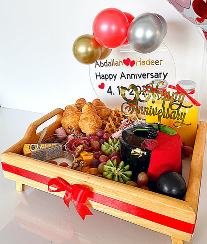 Decorative tray with food items and balloons, featuring a personalized 'Happy Anniversary' message.