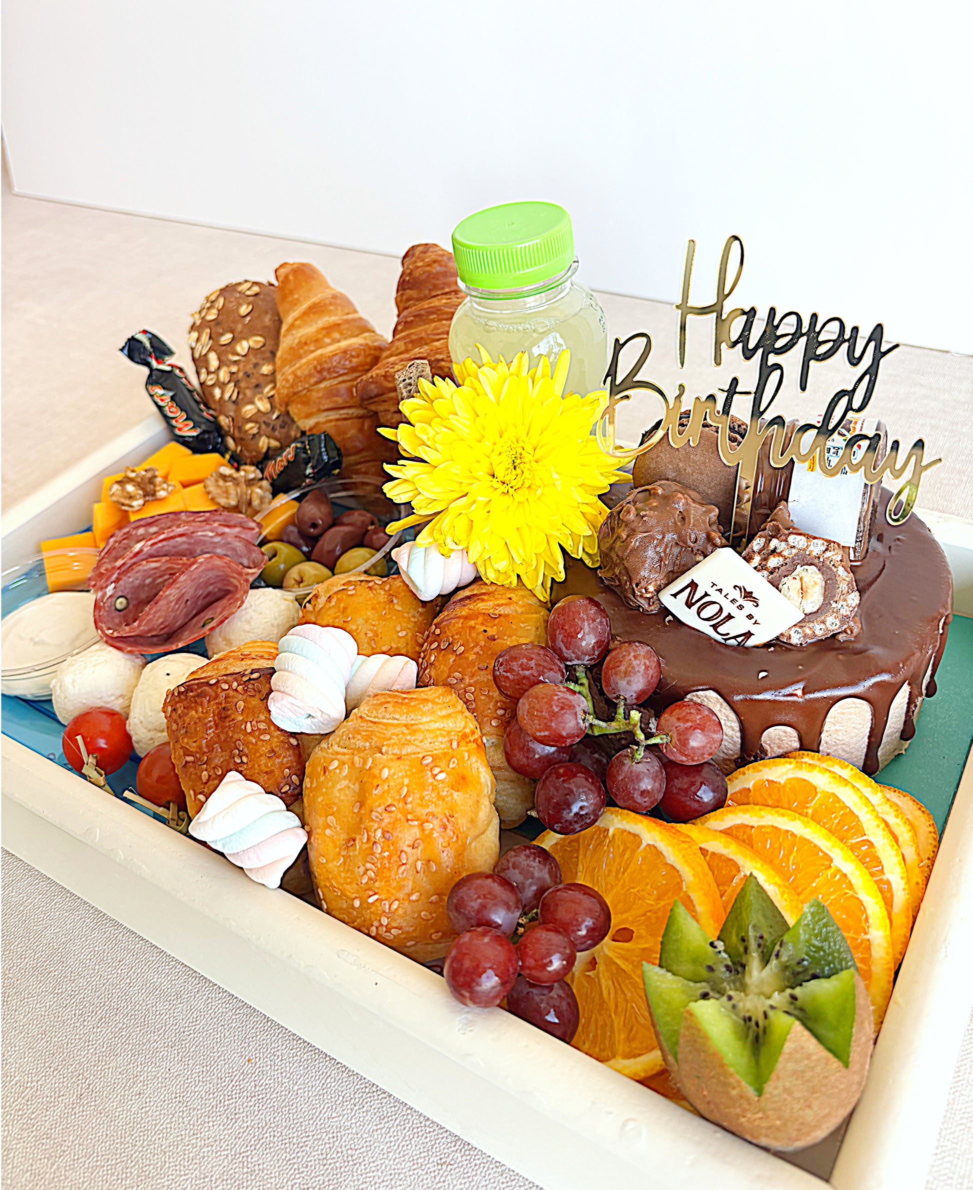 Assorted pastries, fruits, and a small cake with 'Happy Birthday' decoration on a white tray.