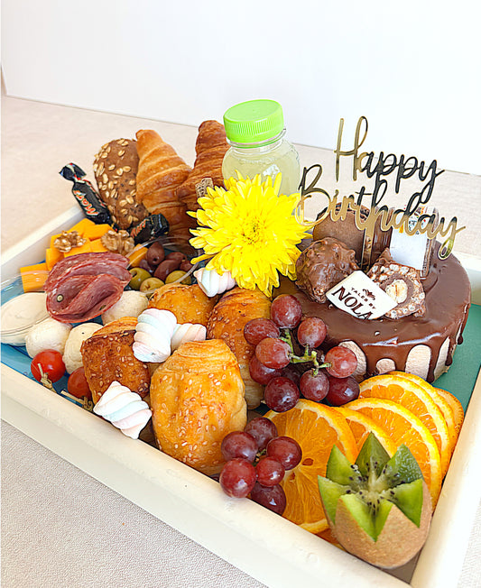 Assorted pastries, fruits, and a small cake with 'Happy Birthday' decoration on a white tray.