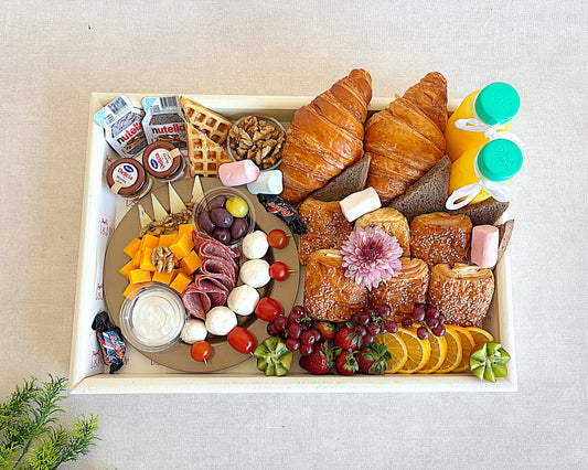 Assorted breakfast items including pastries, fruits, and spreads on a tray.