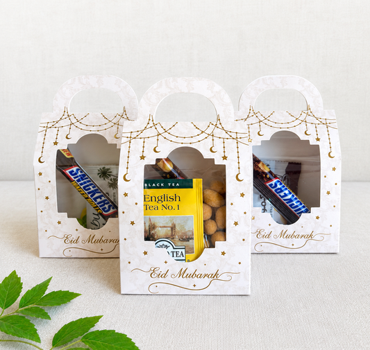 'Eid Mubarak' gift boxes with tea and candy on a light background