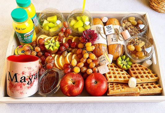 Assorted food items including fruits, waffles, and drinks in a box on a white surface.