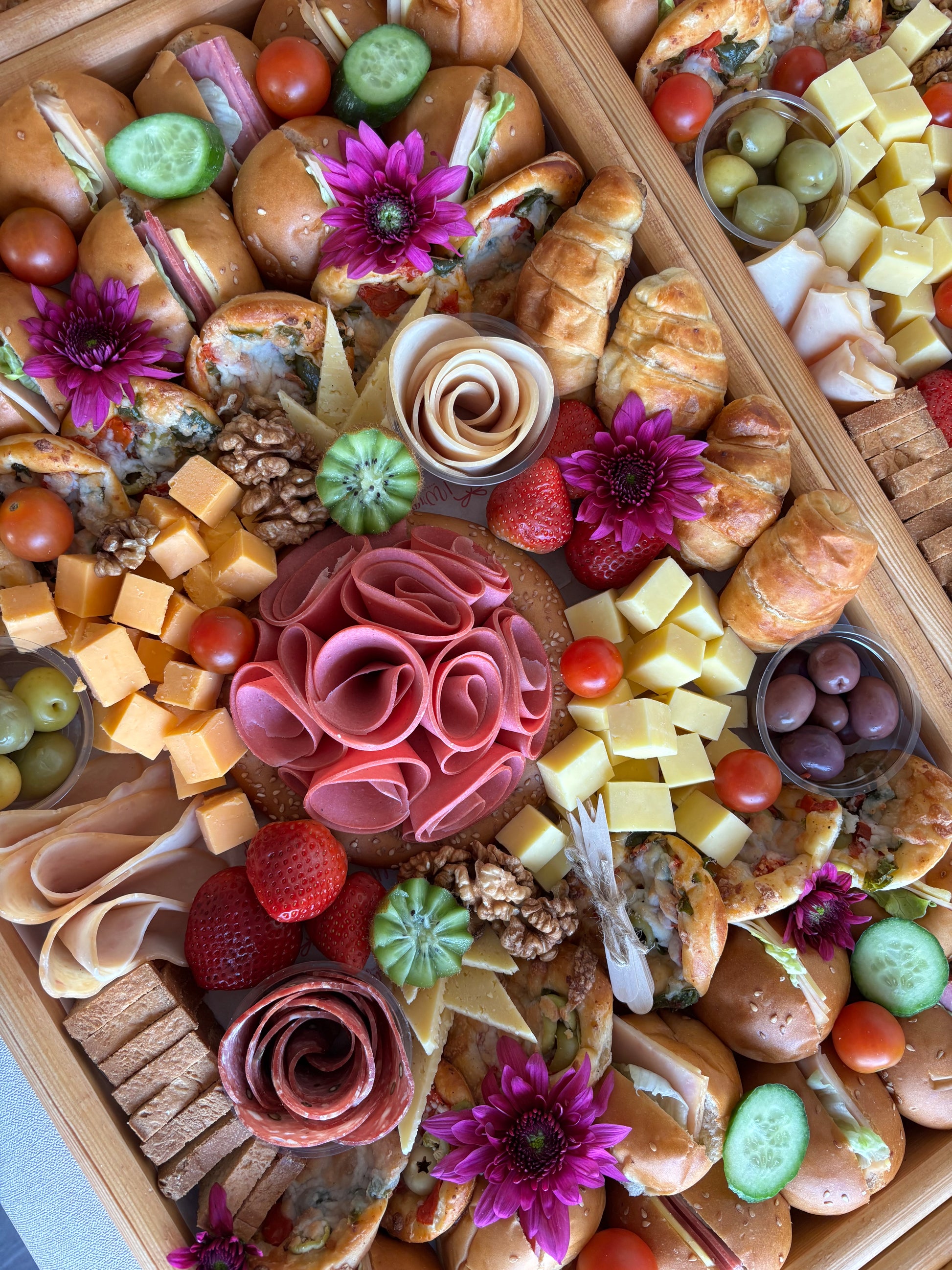 Gourmet charcuterie board with meats, cheeses, bread, and fruits on a wooden board.