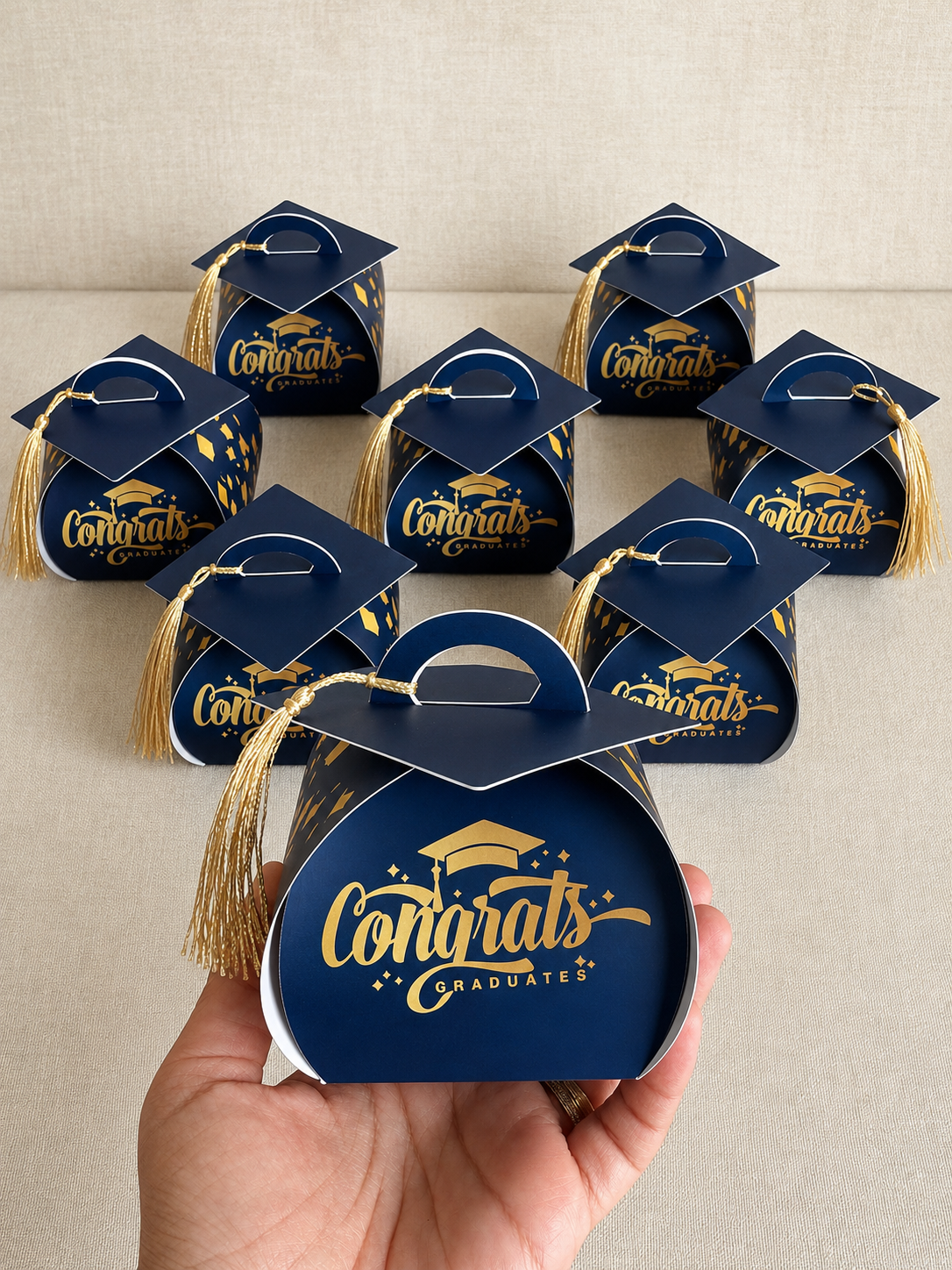 Set of 'Congrats Graduates' gift boxes with tassels on a neutral background