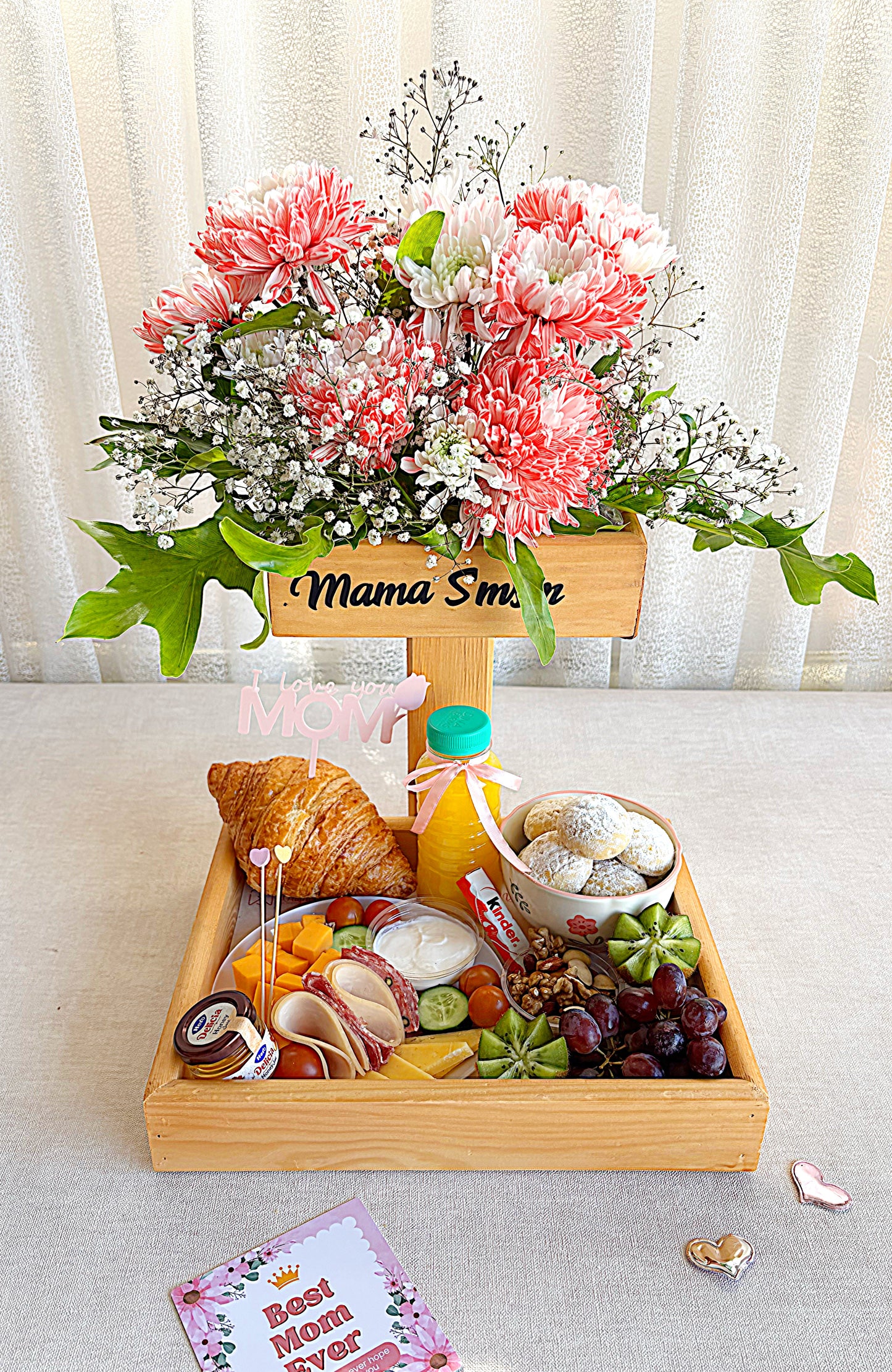 Wooden tray with flowers, fruits, and pastries on a light background